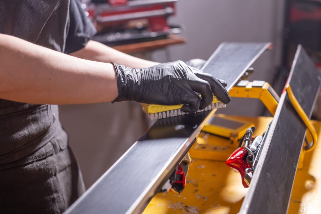 Work and repair concept - a man's hands repairing the ski by rubbing a paraffin